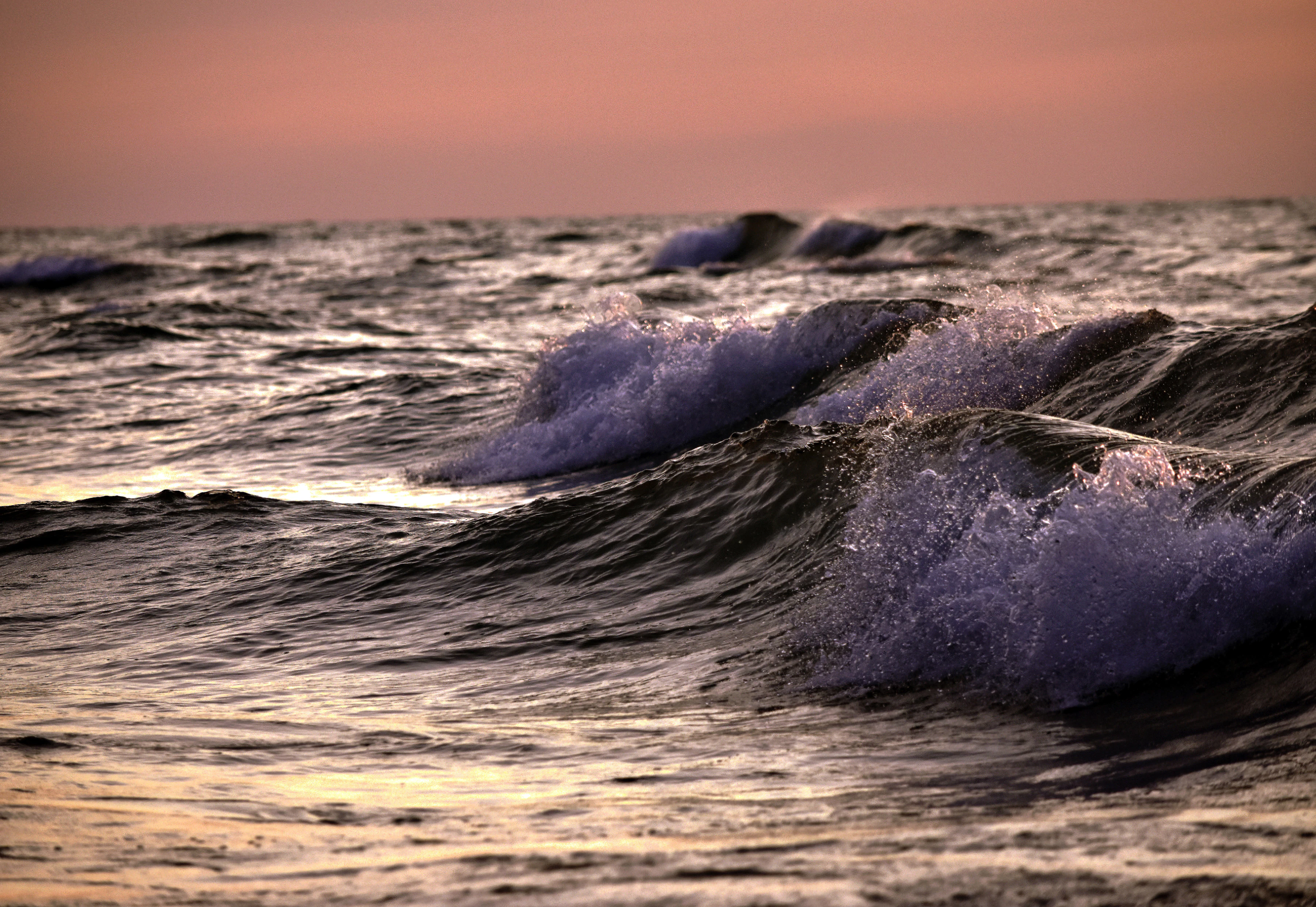 Waves, under soft pale beams of sunlight 